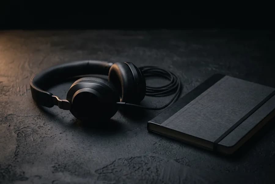 Headset de atendimento ao lado de um caderno sobre mesa escura